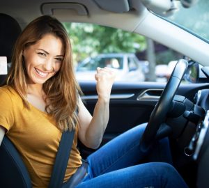 donna felice in auto con patente in mano