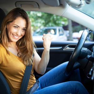 donna felice in auto con patente in mano