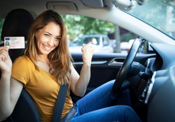 donna felice in auto con patente in mano