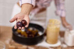 mano di donna con prugne in mano in cucina