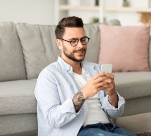 appunti sul cellulare Android, ragazzo al cellulare seduto sotto al divano