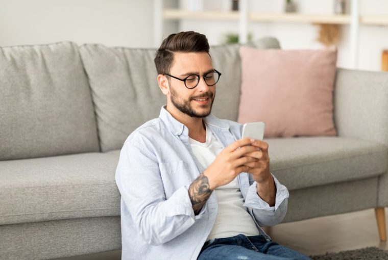 appunti sul cellulare Android, ragazzo al cellulare seduto sotto al divano