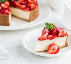 Cheesecake alle fragole, una fetta in piatto e il resto sul vassoio