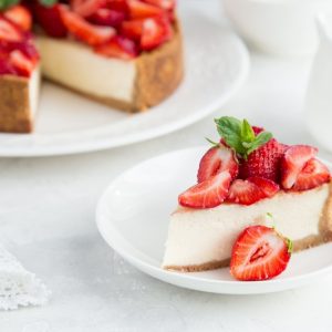 Cheesecake alle fragole, una fetta in piatto e il resto sul vassoio