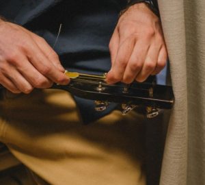 Accordare la chitarra bene richiede metodo e un secondo controllo: Primo piano di un uomo che riaccorda una chitarra…