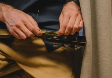 Accordare la chitarra bene richiede metodo e un secondo controllo: Primo piano di un uomo che riaccorda una chitarra…