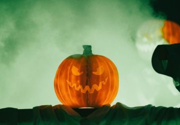 Halloween unisce Ognissanti, riti stagionali e cultura pop: Inquietante zucca di Halloween con un volto minaccioso avvolto…