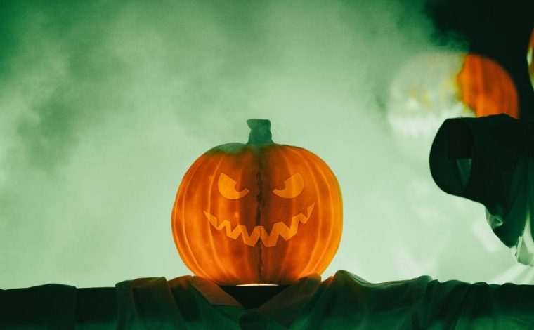 Halloween unisce Ognissanti, riti stagionali e cultura pop: Inquietante zucca di Halloween con un volto minaccioso avvolto…